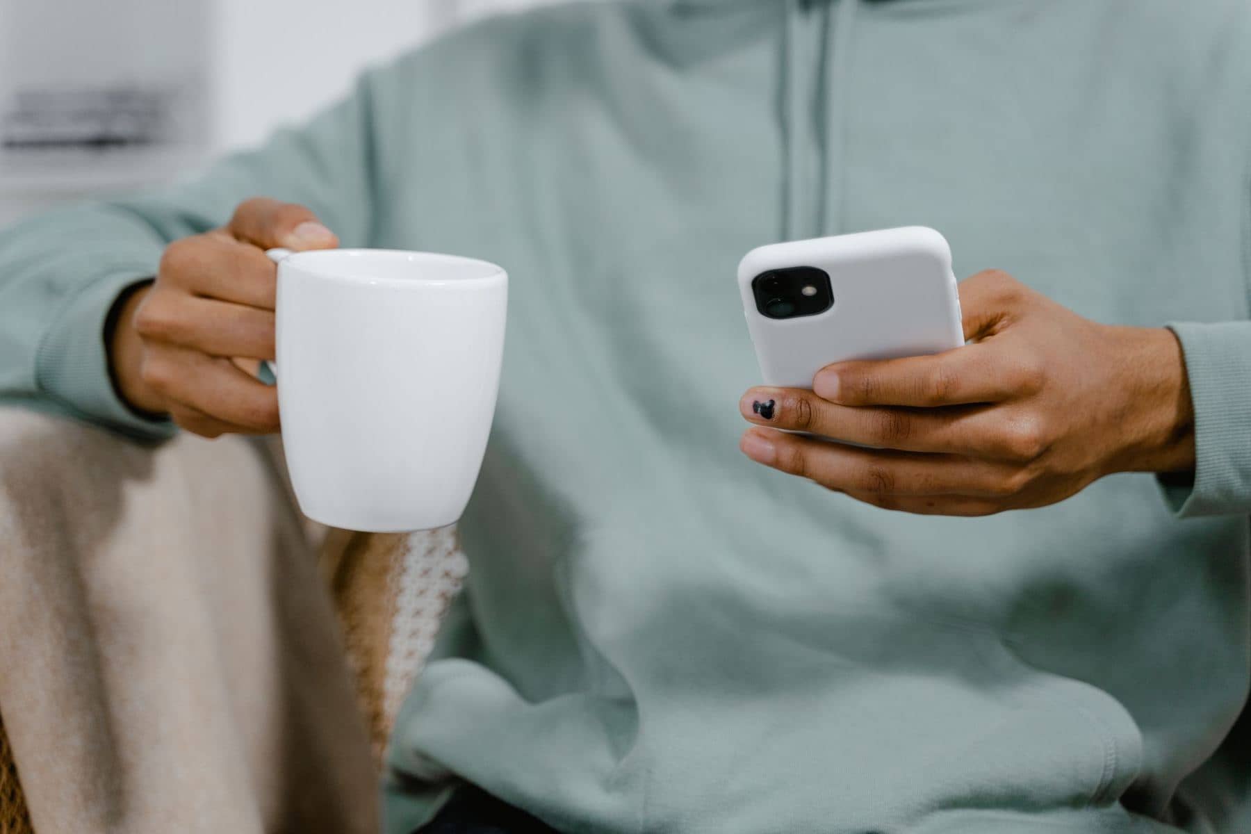 A pair of hands holding a mug of tea and a phone A pair of hands holding a mug of tea and a phone